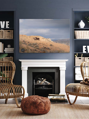 a cozy living room with a fireplace, wicker chairs, and a large framed landscape photograph on the wall.