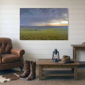 a serene countryside scene with rolling green hills under a dramatic sky, featuring a warm sunset glow.