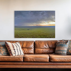a large landscape painting hanging on a wall above a brown leather couch with patterned pillows.