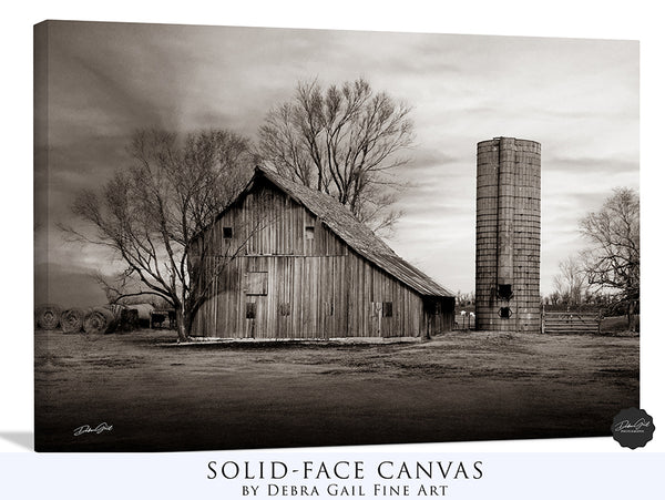 a black and white photo of a barn and silo