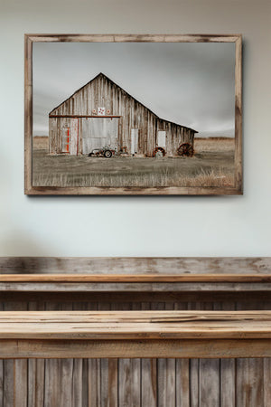 a rustic wooden barn with a tractor parked in front, set against a cloudy sky.
