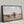 A black float frame canvas print of a herd of longhorn cattle in a dry field under a cloudy sky, with the front cow facing forward.