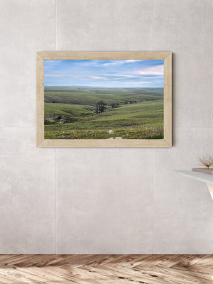 a serene bedroom with a large window overlooking a picturesque countryside landscape. The room features a wooden floor, a white bed, and a wooden dresser. A framed landscape photograph is hanging on the wall, adding a touch of nature to the space.