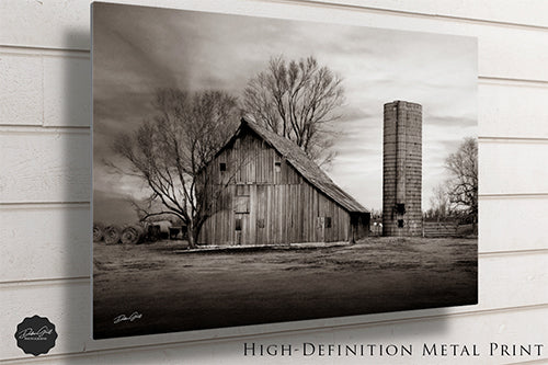 a black and white photo of a barn and silo