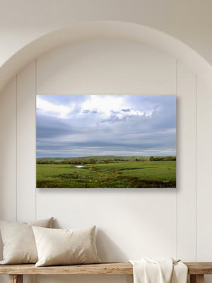 A Flint Hills Kansas fine art canvas print depicting a beautiful green field under a cloudy sky, by Debra Gail.