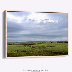 A Flint Hills Kansas fine art natural wood framed canvas print depicting a beautiful green field under a cloudy sky, by Debra Gail.