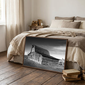 Wood framed black and white canvas of historic Mormon Row barn in Wyoming with dramatic sky and rustic wooden architecture.