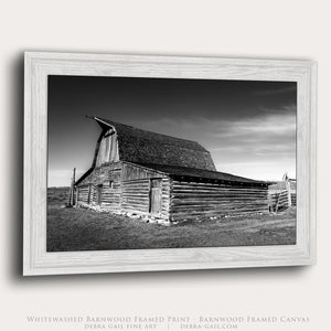 White Barnwood framed black and white photograph of historic Mormon Row barn in Wyoming with dramatic sky and rustic wooden architecture.